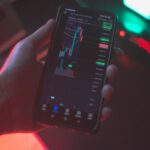 Hand holding smartphone displaying cryptocurrency trading app with financial data.