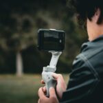 A man uses a smartphone gimbal outdoors, capturing stable video footage.