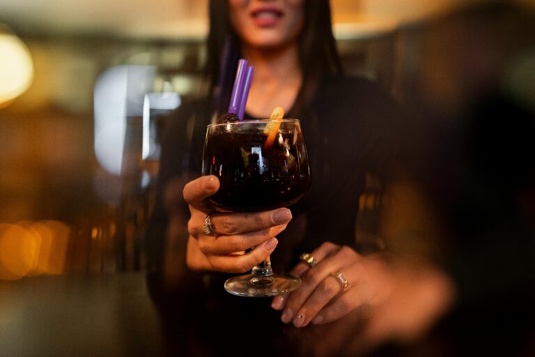 Stylish woman holding a fruity cocktail with straws in an İstanbul bar setting.