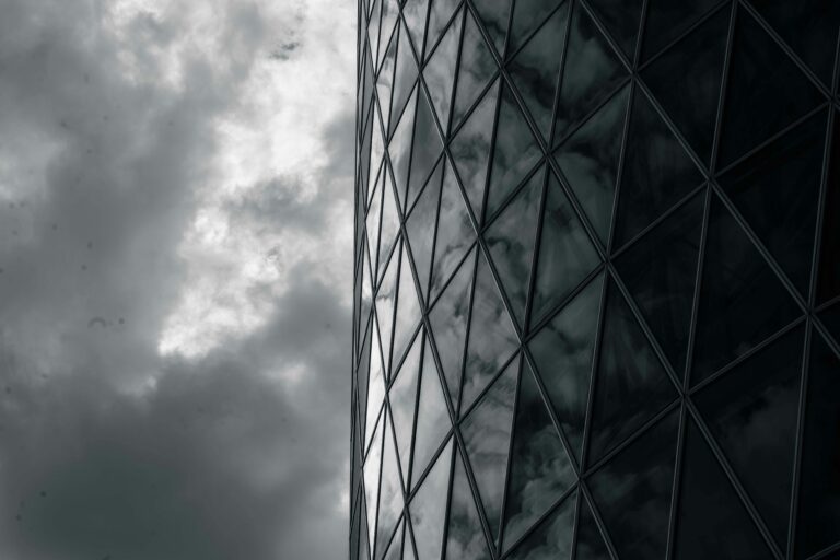 Dark glass facade reflects swirling clouds, creating a dramatic and abstract architectural view.