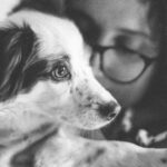 A touching black and white portrait of a girl lovingly hugging her dog.