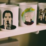 A collection of artistic ceramic mugs featuring graphic designs displayed on a shelf.