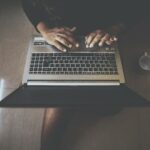 Aerial shot of a person typing on a laptop with a nearby mug. Perfect for technology and lifestyle themes.