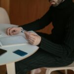 Adult man using tablet and credit card to shop online at home, sitting by table with coffee.