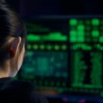 A woman focuses on data displayed on a computer screen in a dark room.
