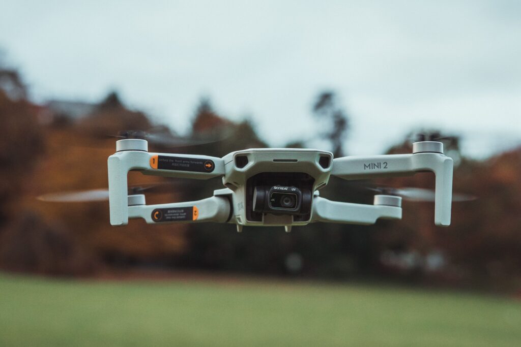 High-resolution image of a DJI Mini 2 drone flying outdoors with a blurred background.