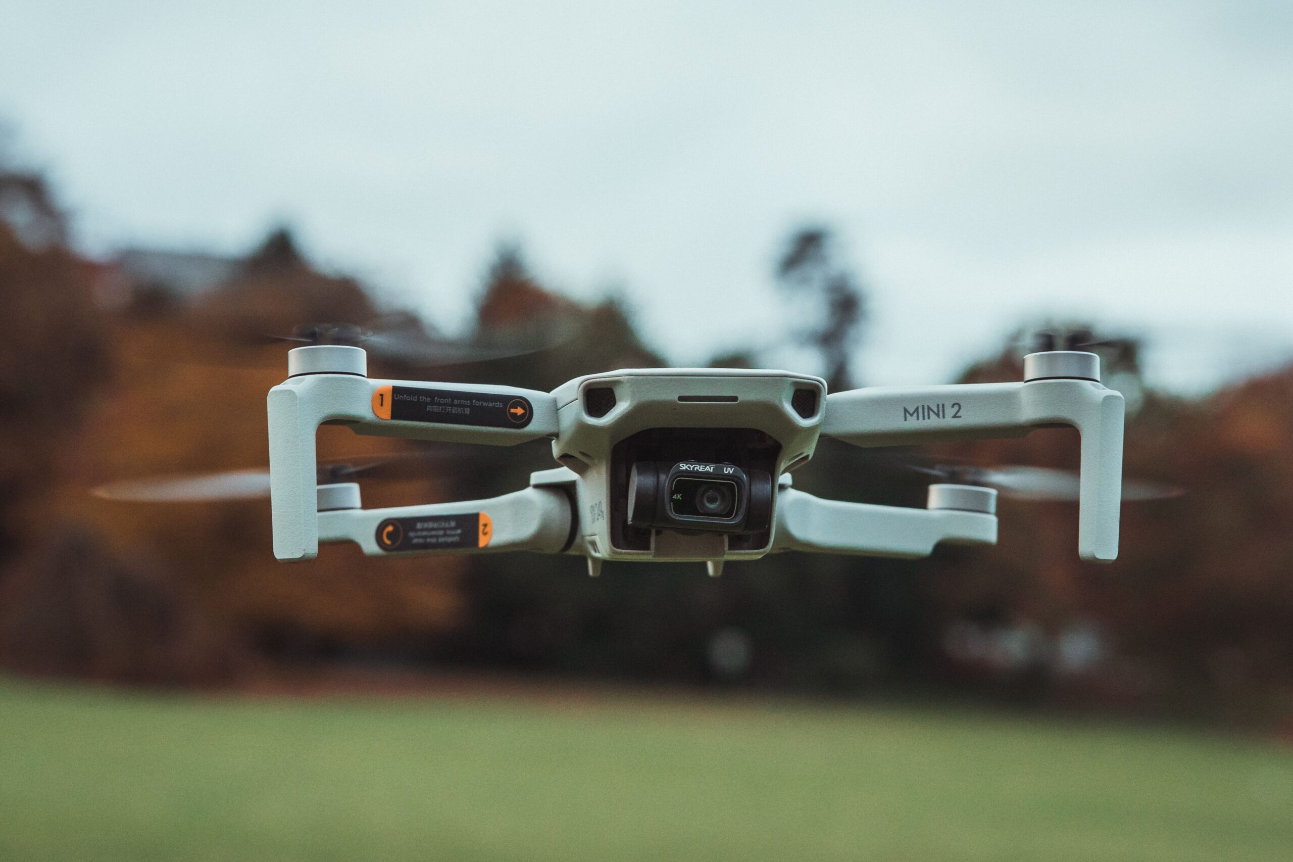 High-resolution image of a DJI Mini 2 drone flying outdoors with a blurred background.