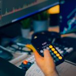 A focused shot of financial trading with screens, calculator, and data charts.